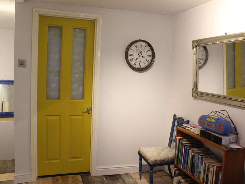 A hallway with a yellow door, clock, mirror, chair, and bookshelf at 4BedHouse/Leominster/Hiking/Castles/Sleeps7/Wifi Leominster