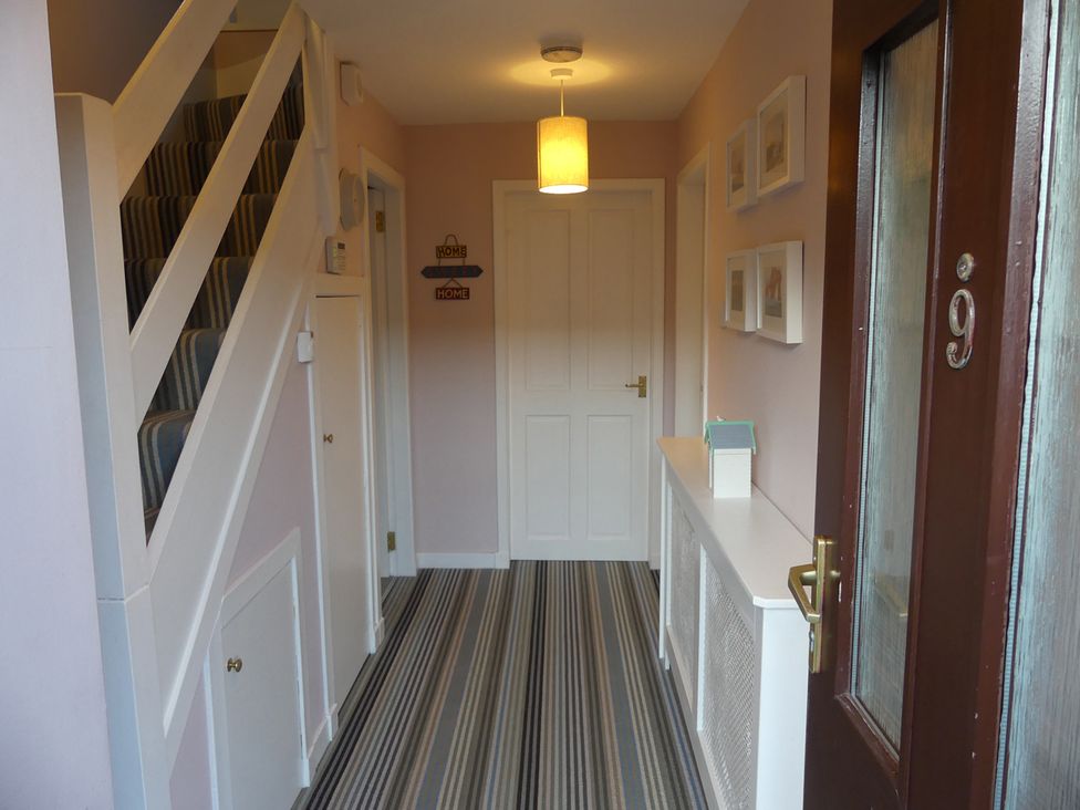 A hallway with a staircase and a console table at Charming Cottage in North Berwick