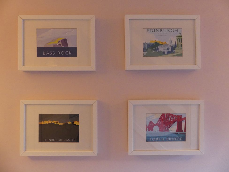 Framed artwork on a wall featuring Bass Rock, Edinburgh, Edinburgh Castle, and Forth Bridge at Charming Cottage in North Berwick