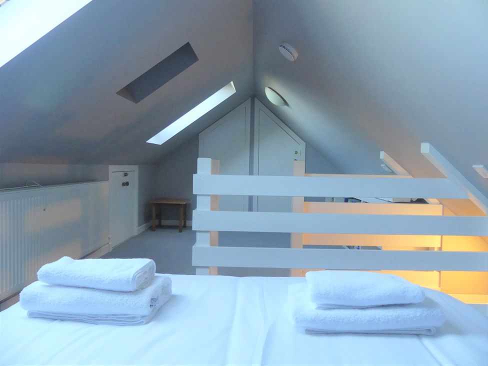 A loft with towels on a bed and a table at Charming Cottage in North Berwick
