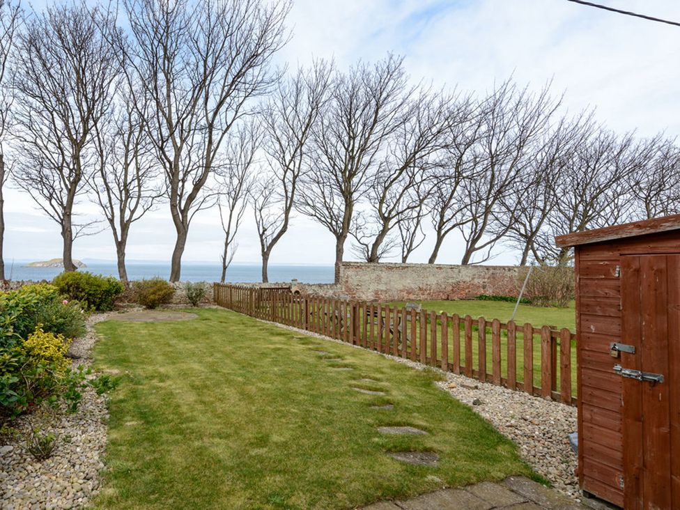 A garden with trees and a wooden fence at Charming Cottage in North Berwick