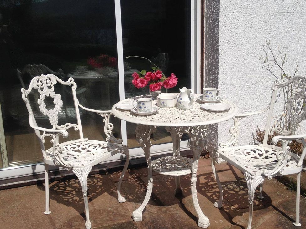 A table with chairs and cups at an outdoor seating area at Apartment Sleeps 2 with Parking, Pets Welcome, Watermillock near Pooley Bridge