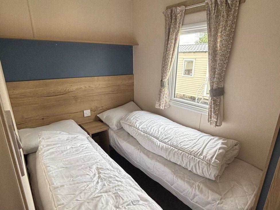 A bedroom with two single beds and a window at Caravan Sleeps 5 - Decking, Parking, Pet Friendly in Blackpool