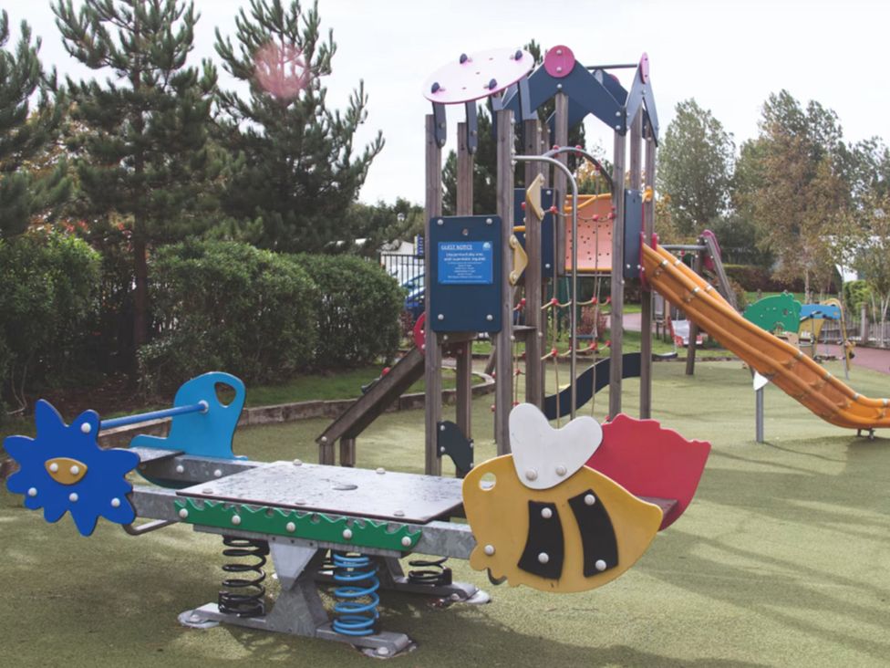 Playground equipment with slide and spring riders in an outdoor play area
