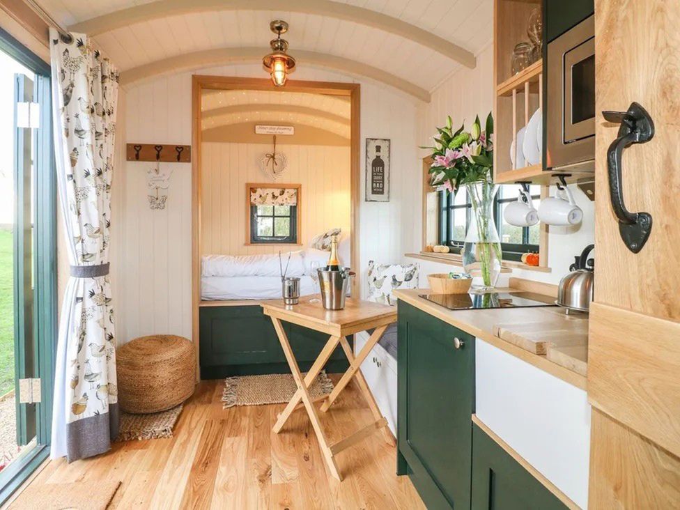 A living room with a bed and table at Shepherd's Hut- Hot Tub- Wellness Spa- Wood Burner Nottingham