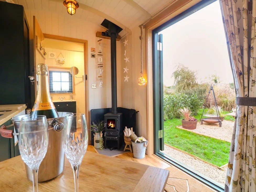 A kitchen area with a wood burner and champagne at Shepherd's Hut- Hot Tub- Wellness Spa- Wood Burner Nottingham