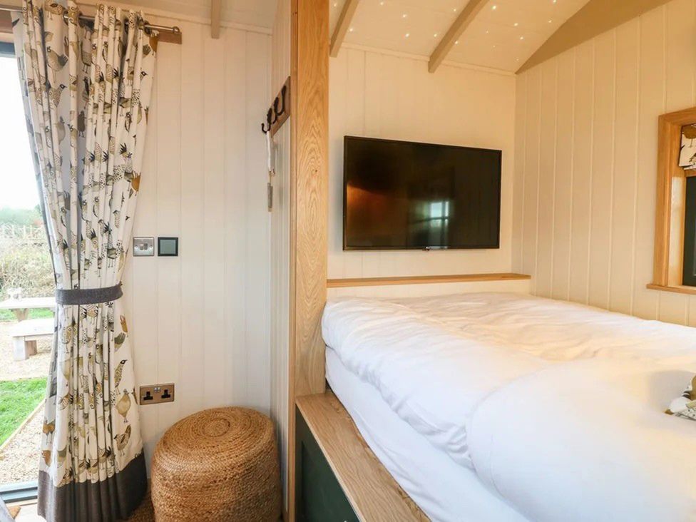 A bedroom with a bed and television at Shepherd's Hut- Hot Tub- Wellness Spa- Wood Burner Nottingham