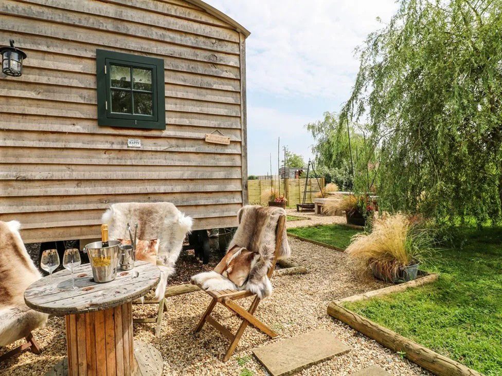An outdoor seating area with wooden table and chairs at Shepherd's Hut- Hot Tub- Wellness Spa- Wood Burner in Nottingham