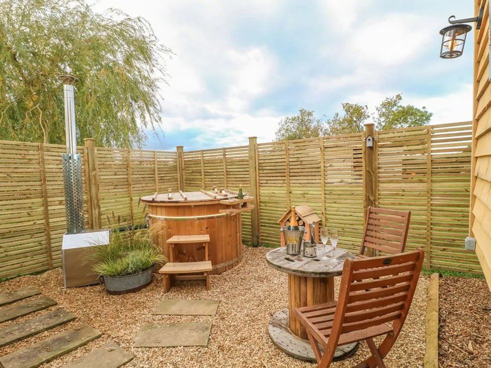 A garden with a hot tub and seating area at Shepherd's Hut- Hot Tub- Wellness Spa- Wood Burner Nottingham