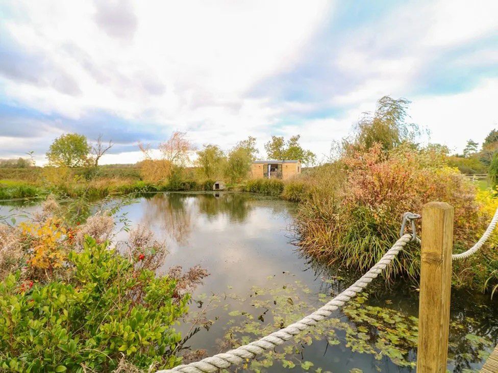 A garden with a pond and a building at Shepherd's Hut- Hot Tub- Wellness Spa- Wood Burner Nottingham