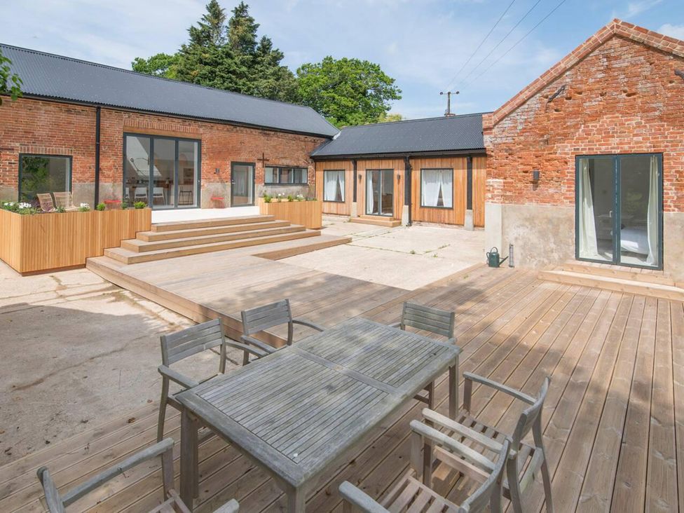 An outdoor area with a wooden table and chairs at Simple Coastal Luxury near Southwold