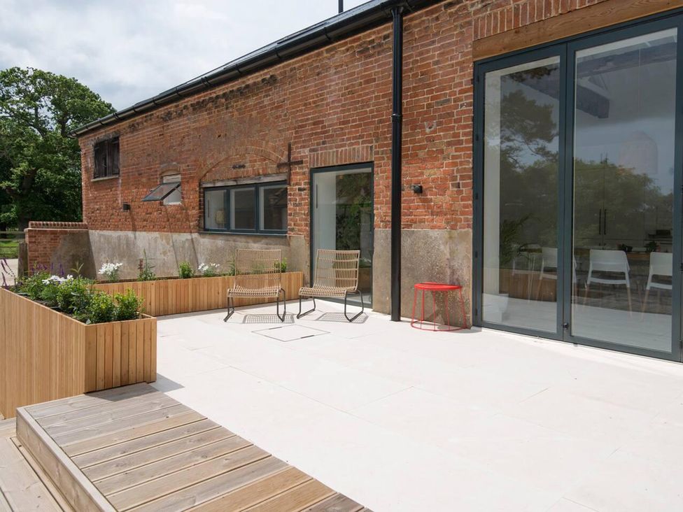 An outdoor area with brick wall and seating at Simple Coastal Luxury near Southwold