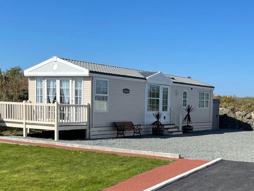 A static caravan with decking and a bench at Chalet Sleeps 4 Near Cymyran Beach in Caergeiliog