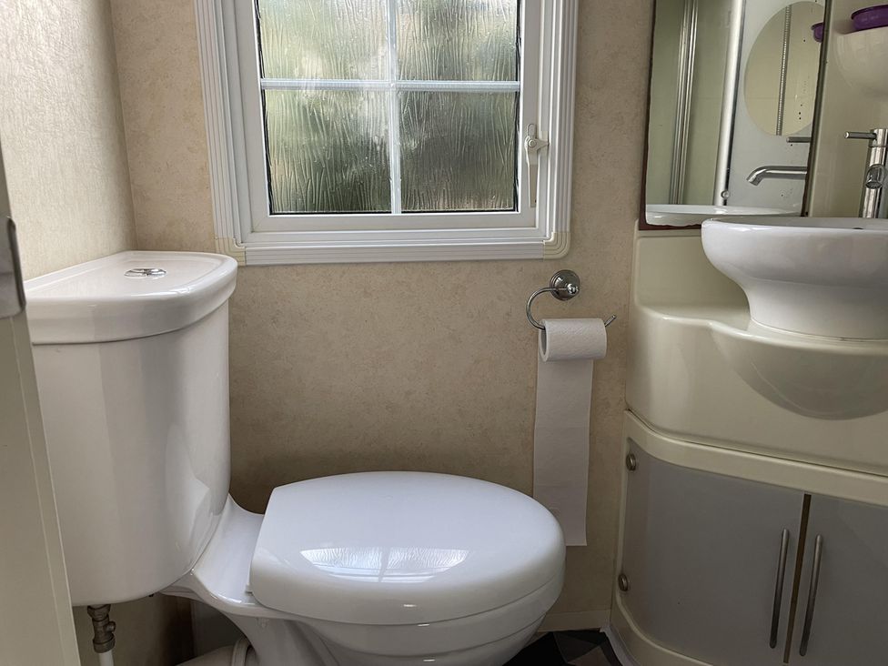 A bathroom with a toilet and sink at Chalet Sleeps 4 Near Cymyran Beach Caergeiliog