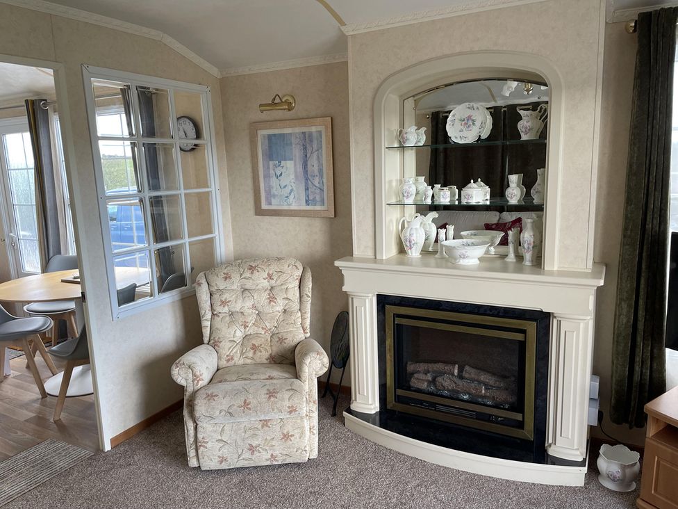 A living room with an armchair and fireplace at Chalet Sleeps 4 Near Cymyran Beach Caergeiliog