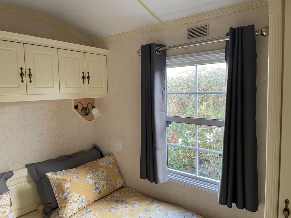 A bedroom with a bed and window at Chalet Sleeps 4 Near Cymyran Beach, Caergeiliog
