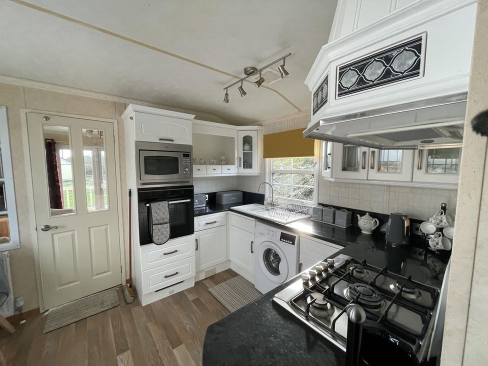 A kitchen with appliances and cabinetry at Chalet Sleeps 4 Near Cymyran Beach Caergeiliog