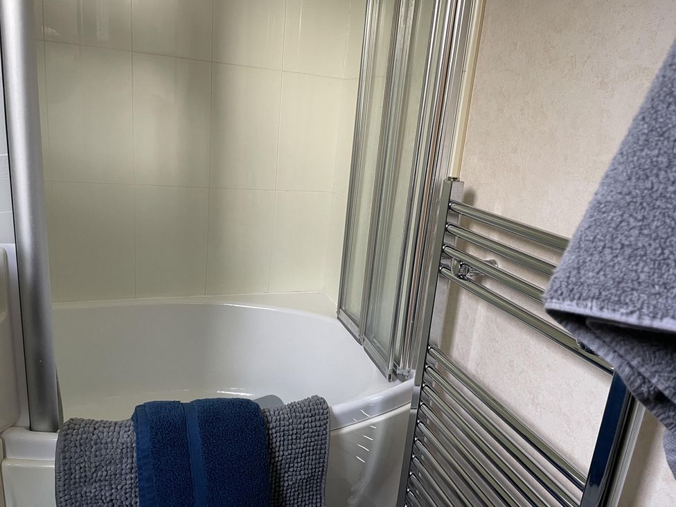 A bathroom with a bathtub and towel rack at Chalet Sleeps 4 Near Cymyran Beach Caergeiliog