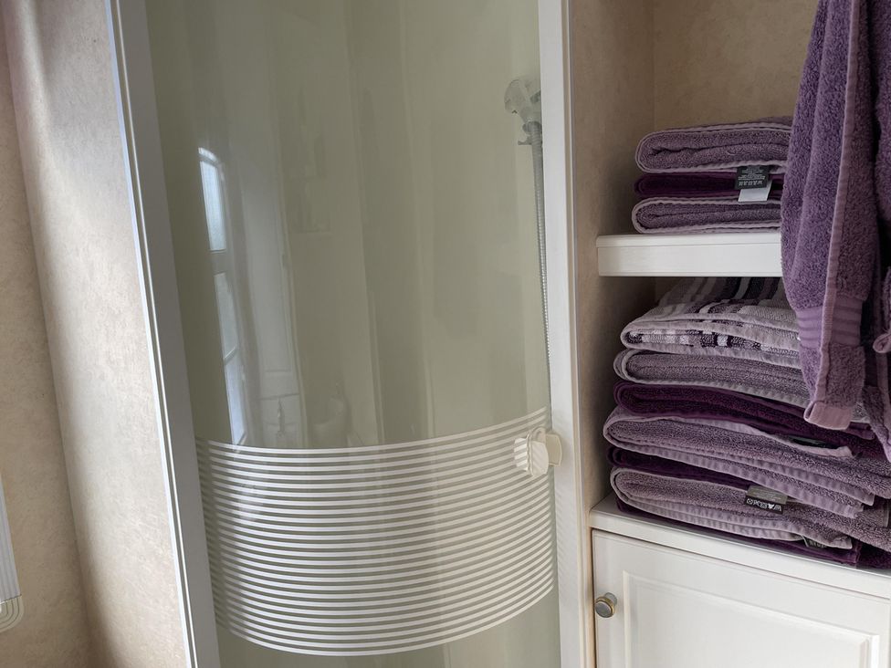 A shower with towels on a shelf at Chalet Sleeps 4 Near Cymyran Beach in Caergeiliog