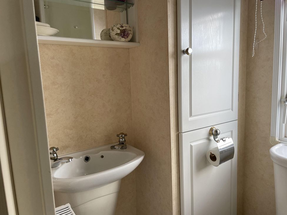 A bathroom with a sink and toilet at Chalet Sleeps 4 Near Cymyran Beach in Caergeiliog