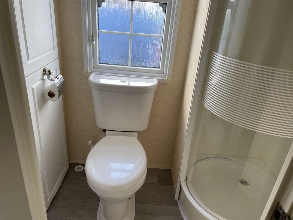 A bathroom with a toilet and shower at Chalet Sleeps 4 Near Cymyran Beach in Caergeiliog