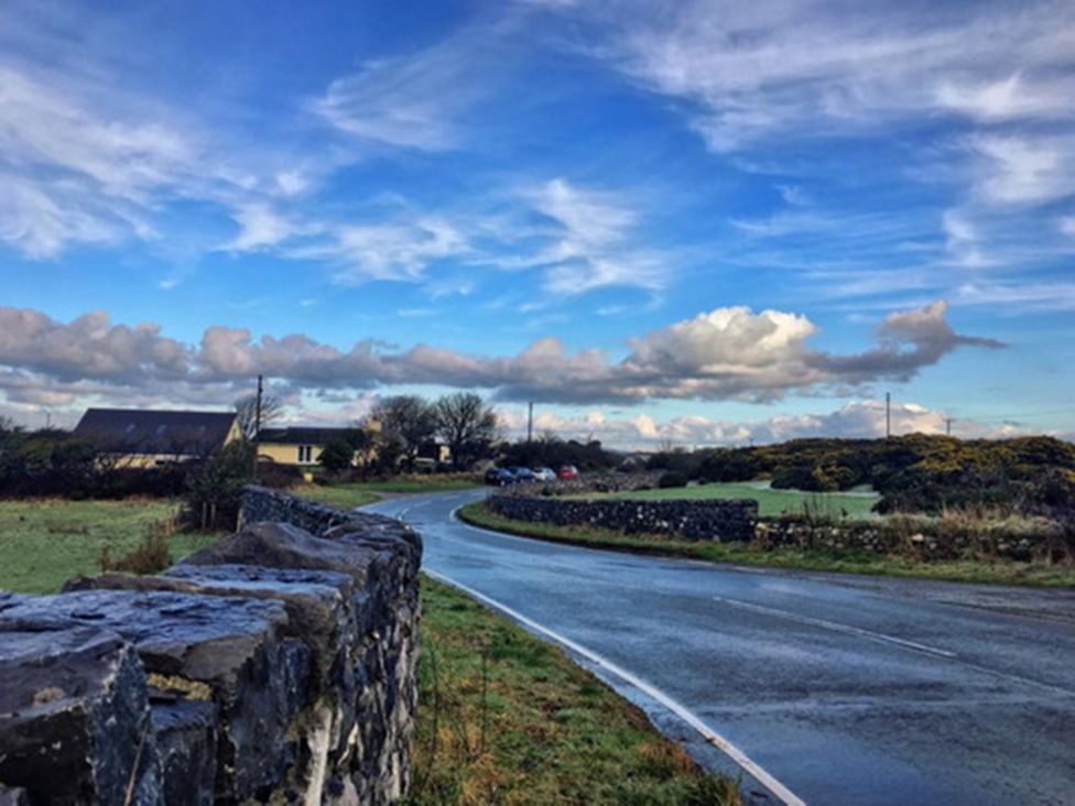 A winding road alongside a stone wall with houses in the distance at Chalet Sleeps 4 Near Cymyran Beach Caergeiliog