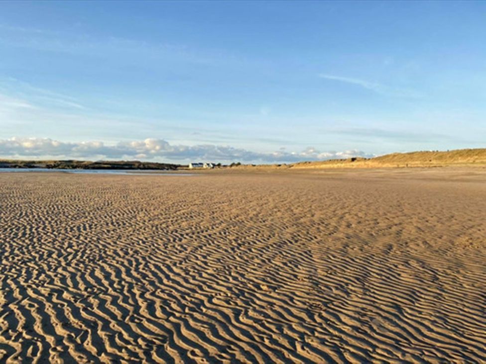 A beach with sand patterns and distant dunes at Chalet Sleeps 4 Near Cymyran Beach Caergeiliog