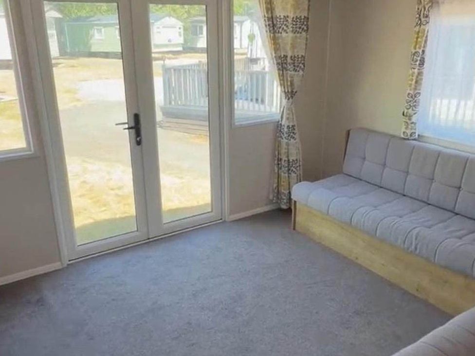 A lounge with double doors and a sofa at Billing Aquadrome Holiday Park - 2 Bedroom, Silver, Northampton