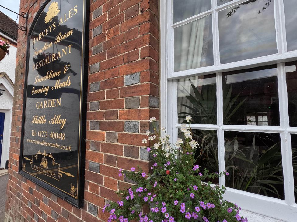 A sign for a restaurant with a window and flowers at Royal Oak Retreat Sleeps 6 Pub Pet Friendly in Barcombe Cross