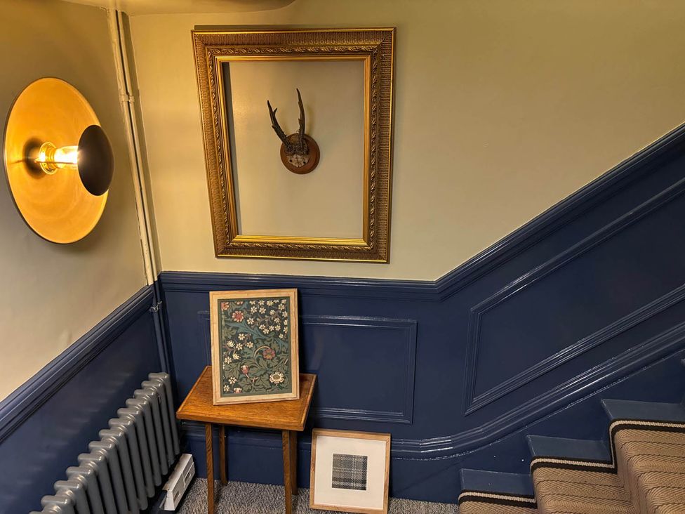 A staircase with framed artwork and wall light at Royal Oak Retreat Sleeps 6 Pub Pet Friendly Barcombe Cross