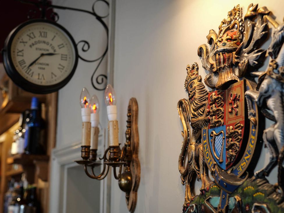 A clock and coat of arms on the wall at Royal Oak Retreat Sleeps 6 Pub Pet Friendly Barcombe Cross