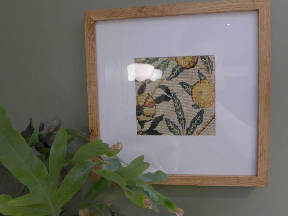 A framed fabric pattern on a green wall with a plant at Royal Oak Retreat Sleeps 6 Pub Pet Friendly in Barcombe Cross