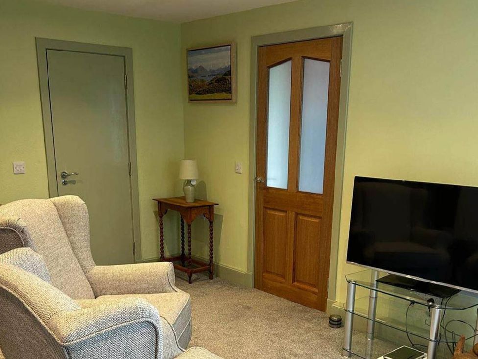 A living room with a sofa, table, lamp, and television at Marsco Apartment Garden Patio Sea Views, Applecross near Lochcarron