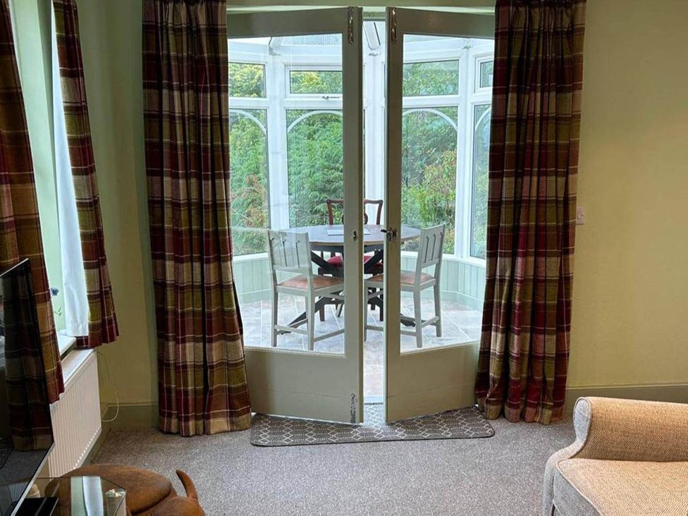 Interior view of a conservatory with door leading outside at Marsco Apartment Garden Patio Sea Views Applecross near Lochcarron