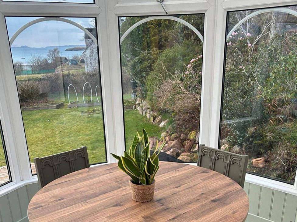 A conservatory with a round table and chairs at Marsco Apartment Garden Patio Sea Views Applecross near Lochcarron