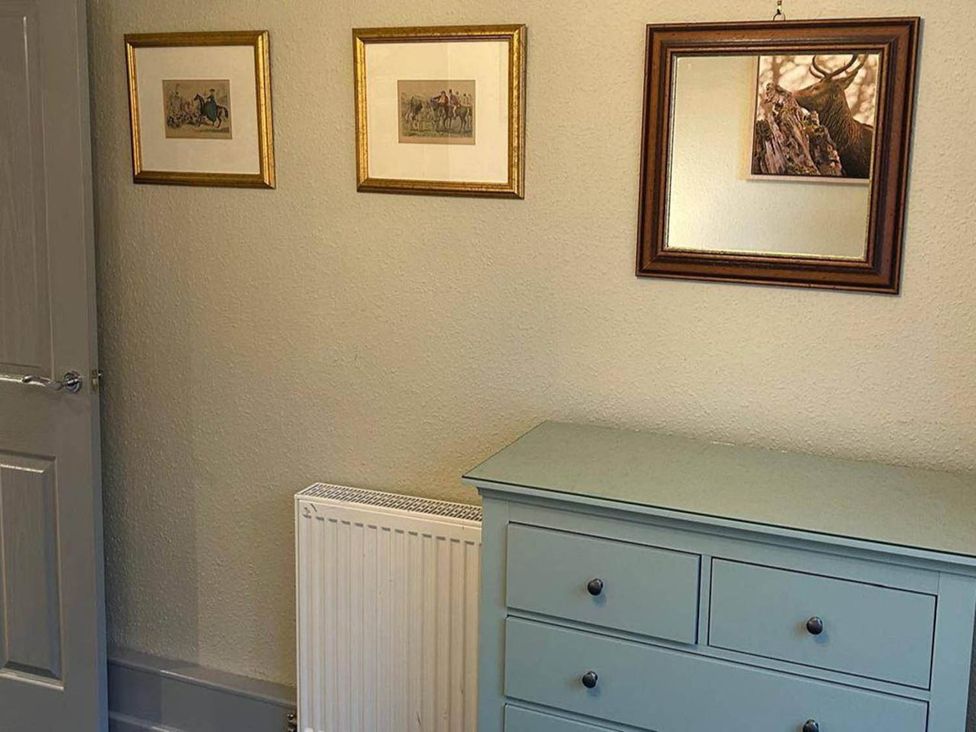 A bedroom with a chest of drawers and framed artworks at Marsco Apartment Garden Patio Sea Views in Applecross near Lochcarron