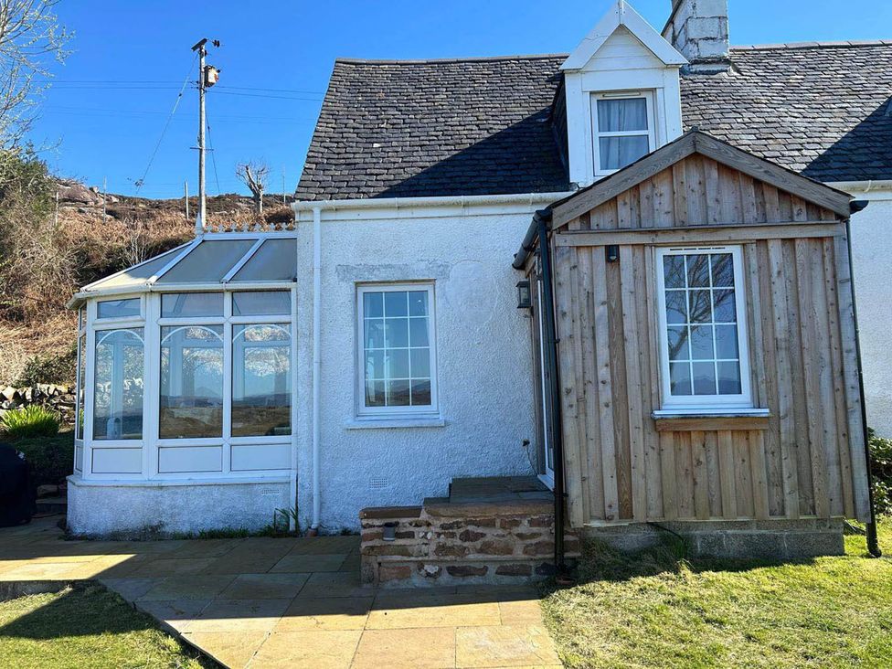 An outdoor view of a house with a conservatory and wooden extension at Marsco Apartment Garden Patio Sea Views Applecross near Lochcarron