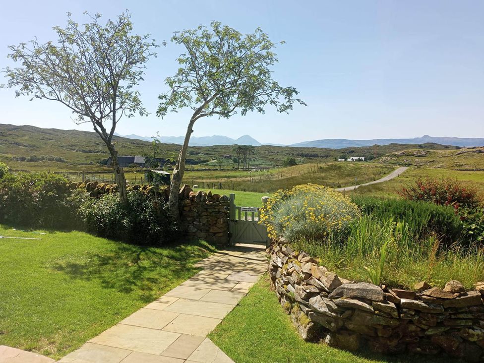 A garden with a stone wall and trees at Marsco Apartment Garden Patio Sea Views in Applecross near Lochcarron
