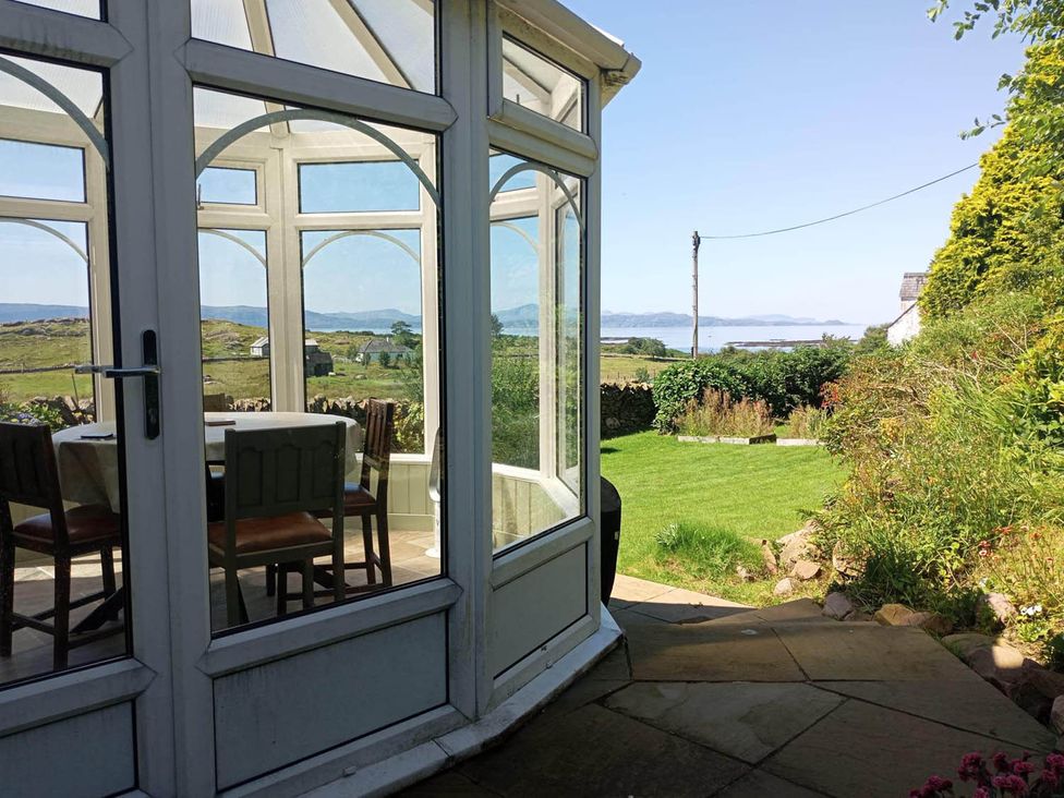 A conservatory with a table and chairs at Marsco Apartment Garden Patio Sea Views in Applecross near Lochcarron