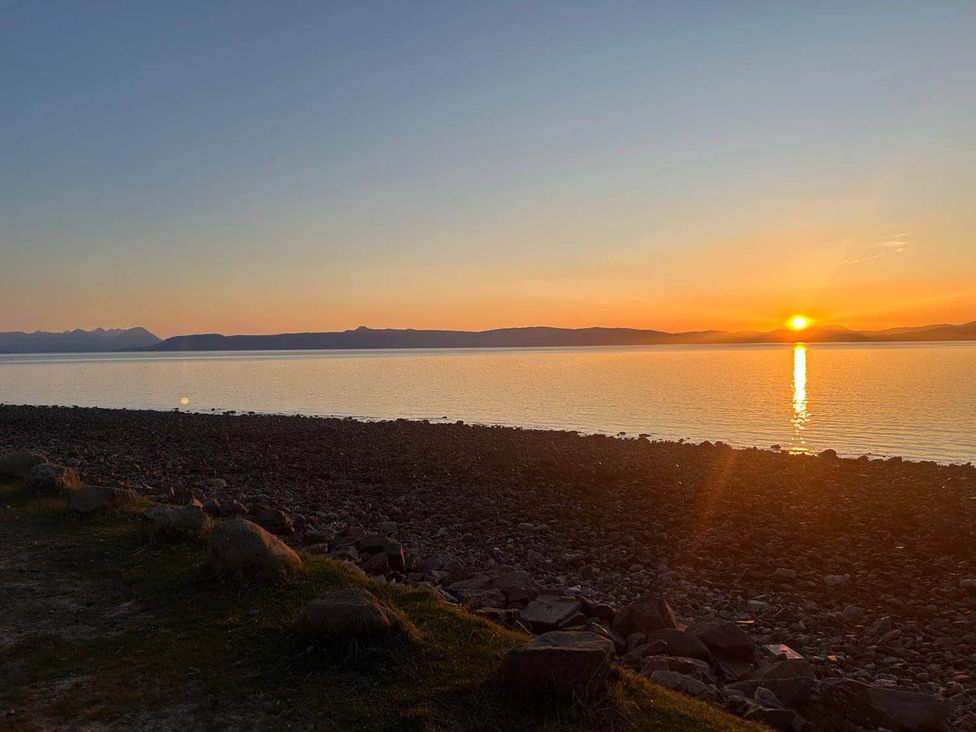 A sunset over the water with rocks along the shoreline at Marsco Apartment Garden Patio Sea Views Applecross near Lochcarron