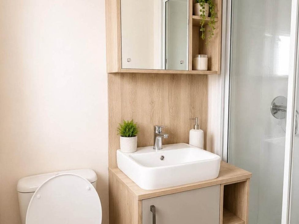 A bathroom with a sink, toilet, mirror, and shower at Tattershall Lakes - Hot Tub - Sleeps 6 - Pets, Tattershall