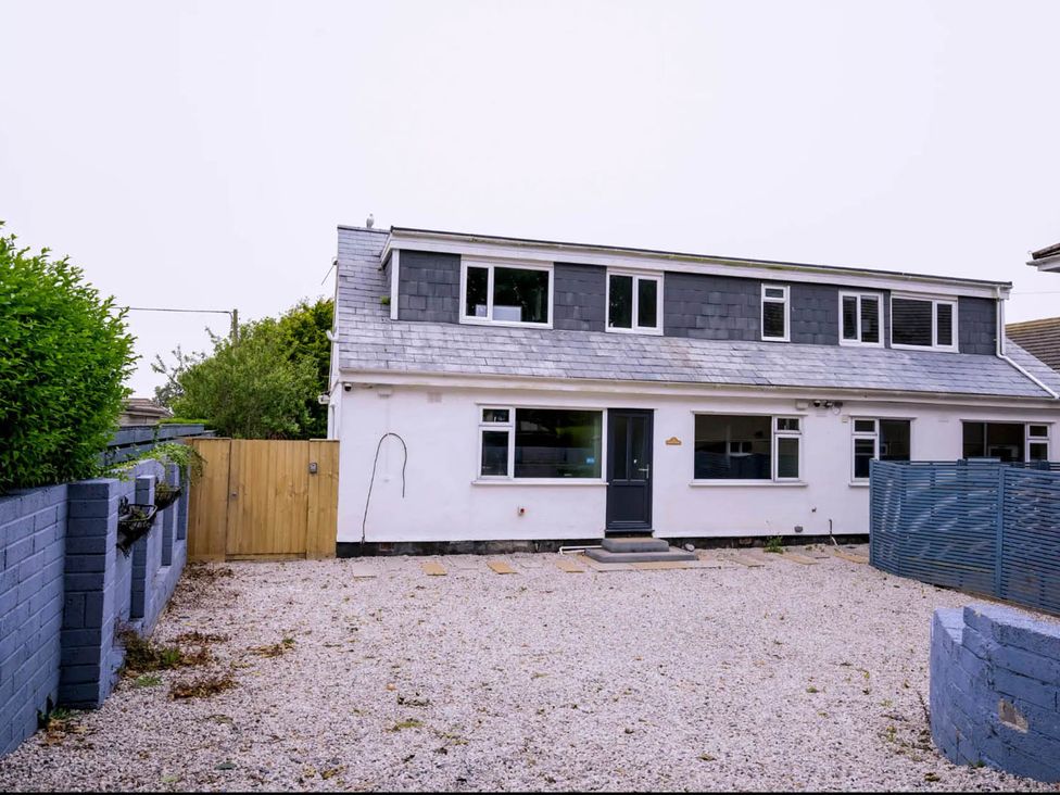 An exterior view of a house with a gravel area and a fence at 2 Bedroom Apartment Sleeps 3 - Garden - Pets in Carbis Bay