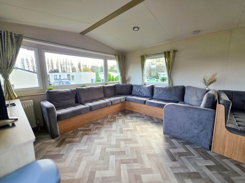 A living room with a large sofa and windows at Static Caravan 3 Bed Sleeps 8 Dog Friendly Parking Northampton