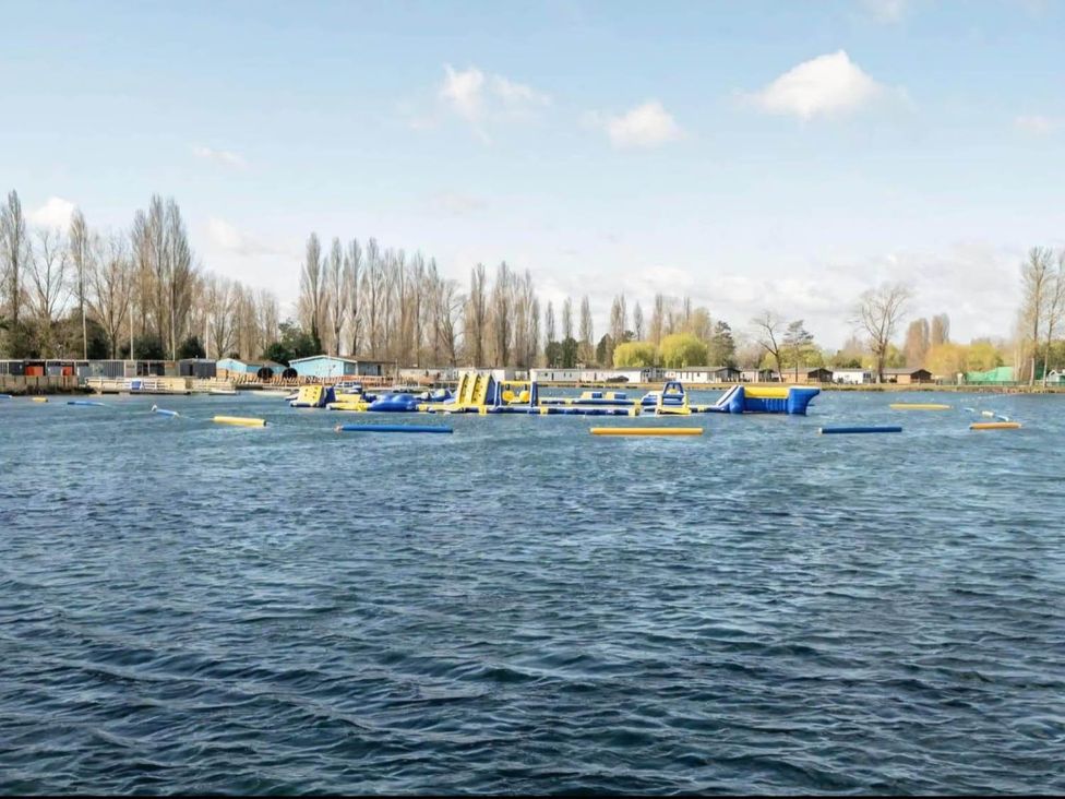 An inflatable obstacle course on water with trailers and trees in the background at Static Caravan 3 Bed Sleeps 8 Dog Friendly Parking Northampton