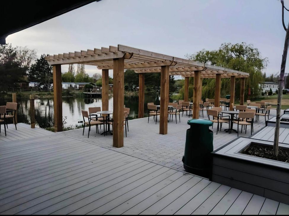 An outdoor area with wooden pergola tables and chairs at Static Caravan 3 Bed Sleeps 8 Dog Friendly Parking Northampton