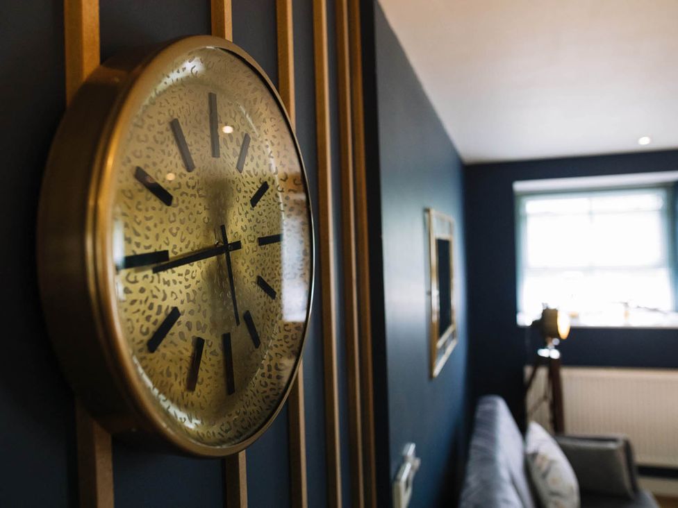 A wall with a clock and a window in a living room at Snowdon Studio Apartment in Tal-y-cafn near Llandudno Junction