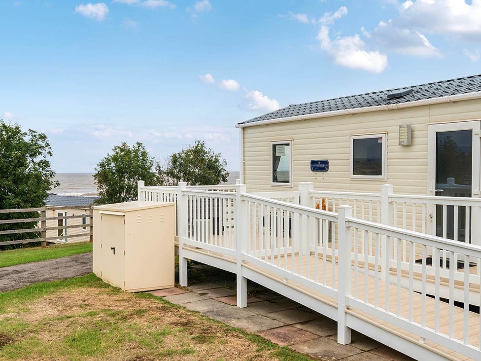 A cabin with a deck and storage unit at Cabin - Sleeps 4 - Pets Ok - Balcony - Parking Haven Park, Doniford Bay near Watchet