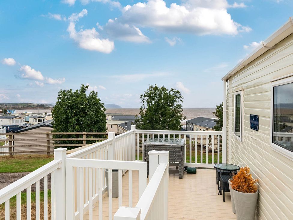An outdoor area with a deck and chairs at Cabin - Sleeps 4 - Pets Ok - Balcony - Parking in Haven Park, Doniford Bay near Watchet