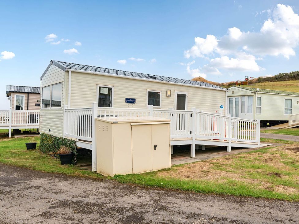 A mobile home with a deck and storage unit at Cabin - Sleeps 4 - Pets Ok - Balcony - Parking Haven Park, Doniford Bay near Watchet