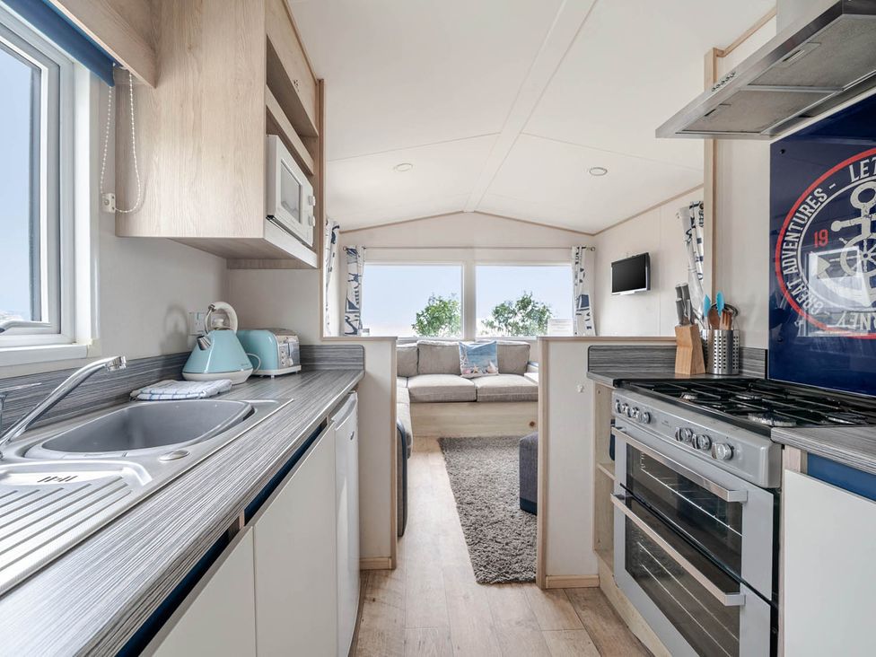 A kitchen with appliances and a couch at Cabin - Sleeps 4 - Pets Ok - Balcony - Parking in Haven Park, Doniford Bay near Watchet
